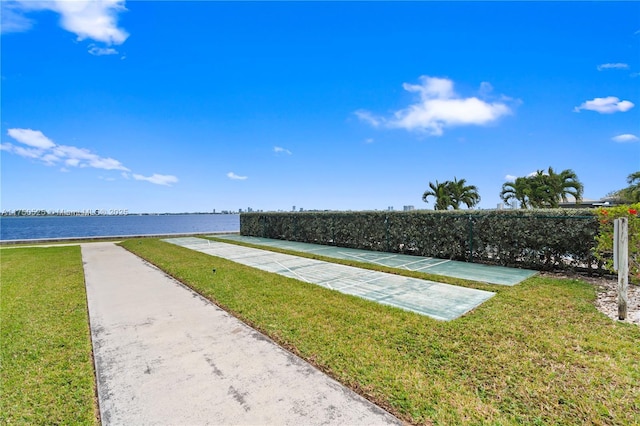 exterior space featuring a water view, a yard, and shuffleboard