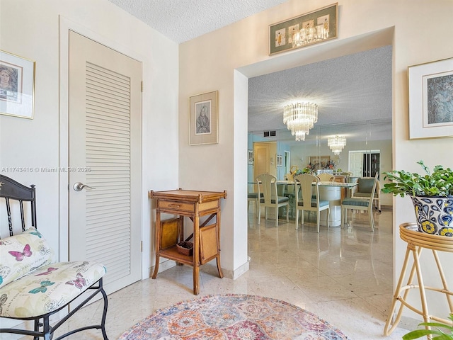 interior space featuring baseboards, visible vents, a chandelier, and a textured ceiling