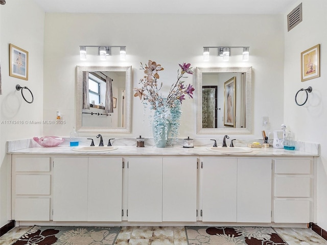 bathroom with double vanity, visible vents, and a sink