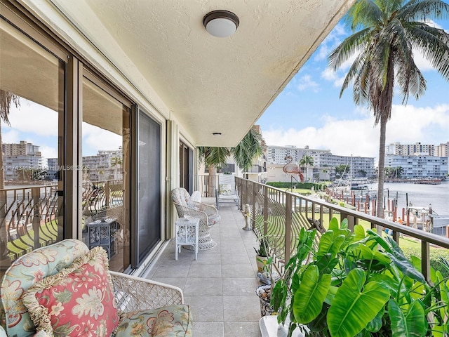 balcony with a water view, a sunroom, and a view of city