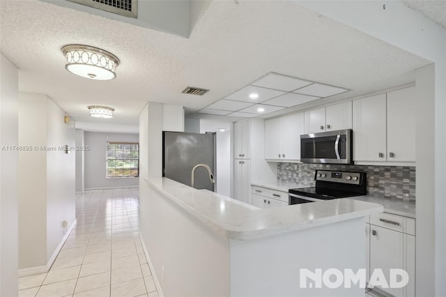 kitchen featuring stainless steel appliances, light countertops, visible vents, white cabinetry, and a peninsula