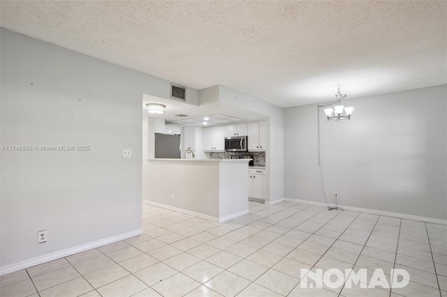 kitchen featuring stainless steel appliances, a peninsula, visible vents, white cabinetry, and light countertops