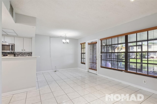 empty room featuring plenty of natural light, a textured ceiling, visible vents, and a notable chandelier