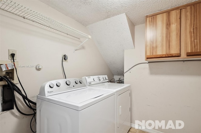 laundry room featuring a textured ceiling, washing machine and clothes dryer, and cabinet space