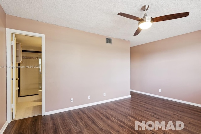 unfurnished room featuring dark wood-style floors, a textured ceiling, visible vents, and baseboards