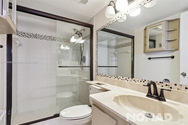 bathroom featuring tasteful backsplash, a shower stall, vanity, and toilet