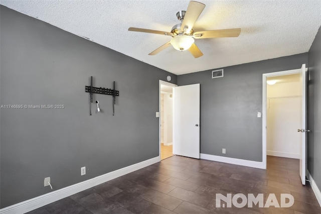 unfurnished bedroom with a textured ceiling, ceiling fan, visible vents, and baseboards