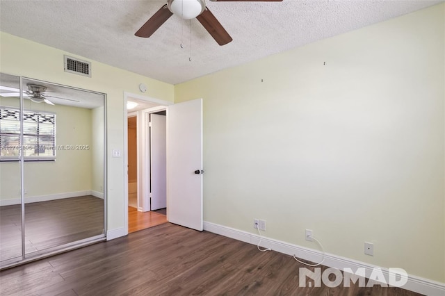 unfurnished bedroom with baseboards, a textured ceiling, visible vents, and dark wood-type flooring