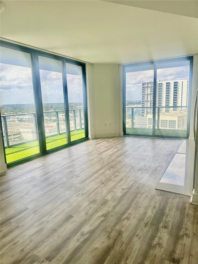 empty room featuring floor to ceiling windows, a city view, and wood finished floors