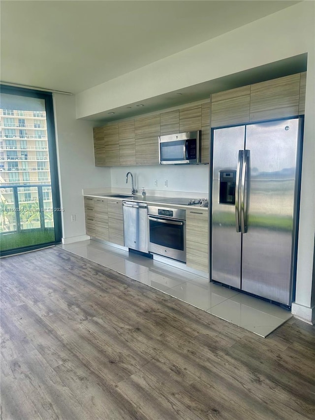 kitchen with stainless steel appliances, a sink, light countertops, expansive windows, and modern cabinets