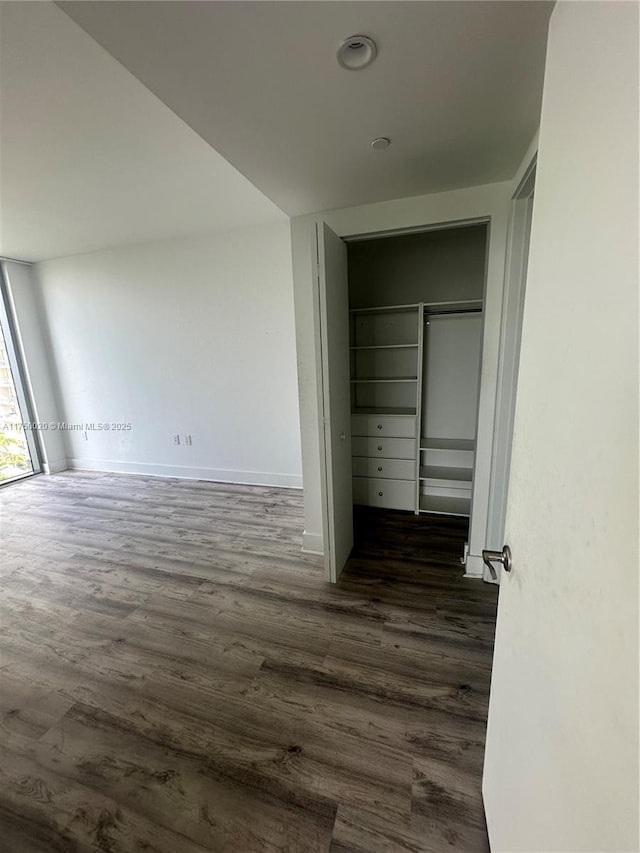 hall featuring baseboards and dark wood-type flooring