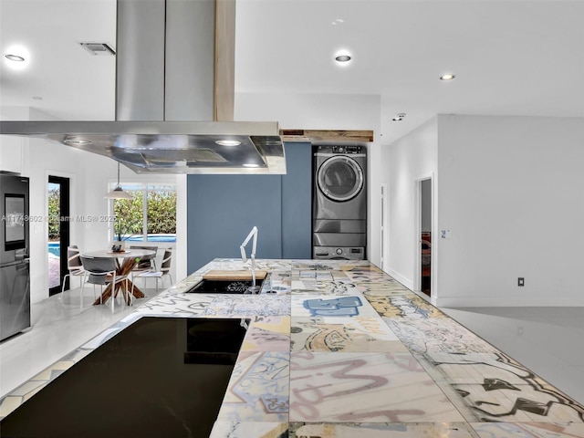 kitchen with recessed lighting, a sink, stacked washing maching and dryer, smart refrigerator, and island exhaust hood