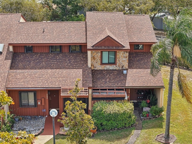 view of front of property featuring stone siding, a shingled roof, and a front yard