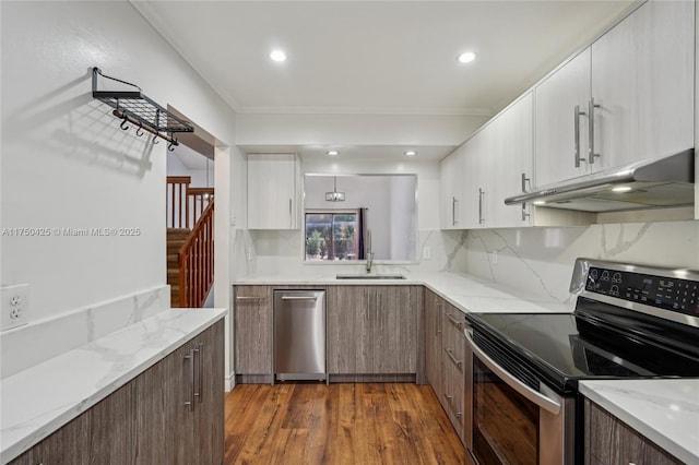 kitchen with white cabinets, a sink, appliances with stainless steel finishes, under cabinet range hood, and dark wood-type flooring