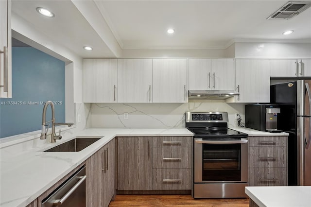 kitchen featuring a sink, visible vents, stainless steel appliances, under cabinet range hood, and modern cabinets