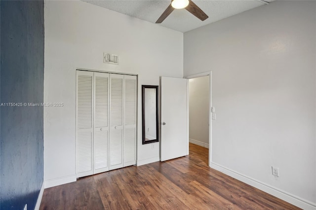 unfurnished bedroom featuring a closet, ceiling fan, wood finished floors, baseboards, and lofted ceiling
