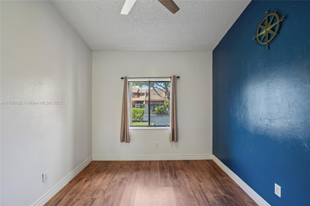 empty room featuring baseboards, wood finished floors, a ceiling fan, and a textured ceiling