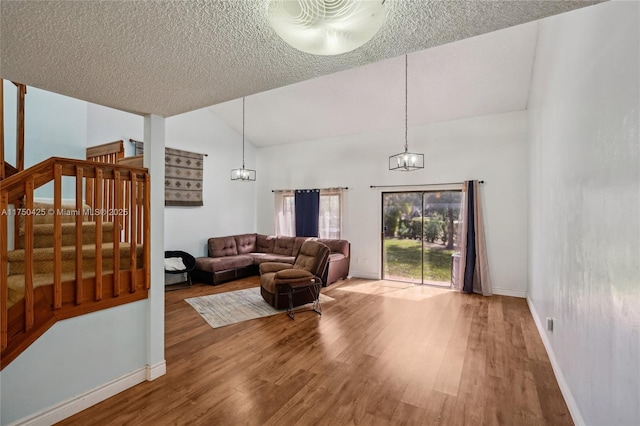 living area featuring baseboards, wood finished floors, a chandelier, and stairs