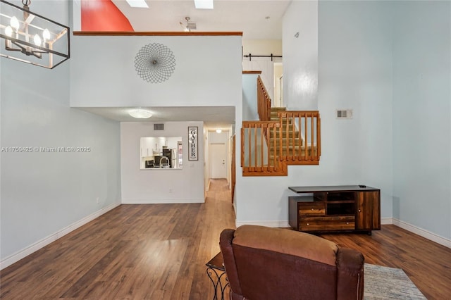 living room with wood finished floors, a barn door, a towering ceiling, and baseboards
