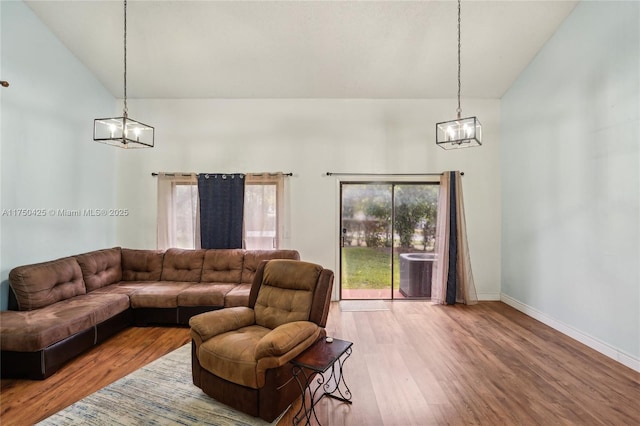 living room with high vaulted ceiling, wood finished floors, a chandelier, and baseboards