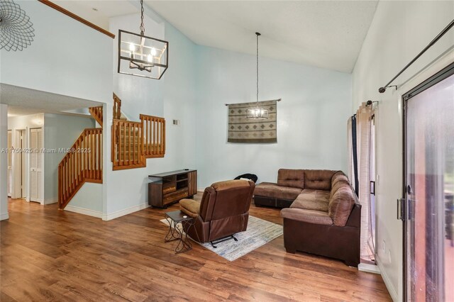 living area with an inviting chandelier, high vaulted ceiling, wood finished floors, and stairs
