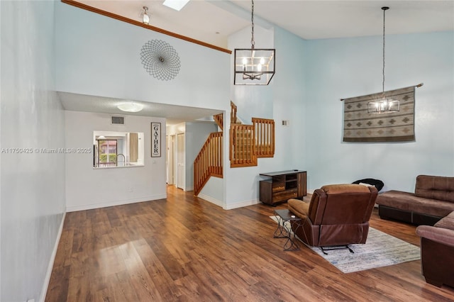 living room with wood finished floors, stairs, a chandelier, baseboards, and high vaulted ceiling