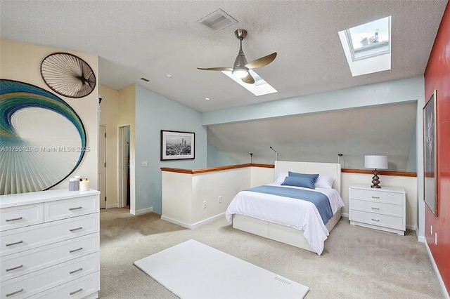 bedroom with visible vents, vaulted ceiling with skylight, light carpet, and baseboards