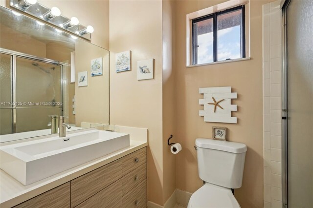 full bathroom featuring a stall shower, toilet, and vanity