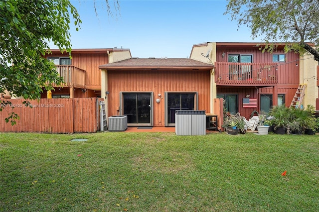 rear view of house with fence, cooling unit, and a lawn