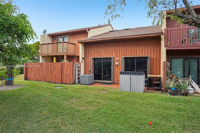 rear view of house featuring fence, a yard, cooling unit, and a balcony