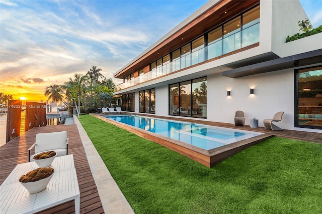 view of swimming pool featuring a pool with connected hot tub and a lawn