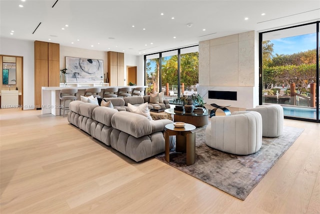 living room with a wall of windows, recessed lighting, and light wood finished floors