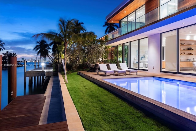 view of swimming pool with a fenced in pool, a water view, and a lawn