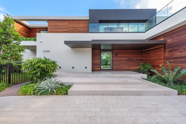 property entrance with fence and stucco siding