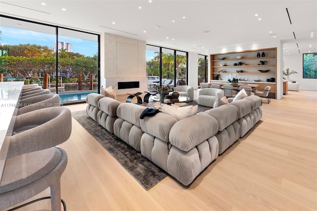 living room with light wood-type flooring, plenty of natural light, floor to ceiling windows, and recessed lighting