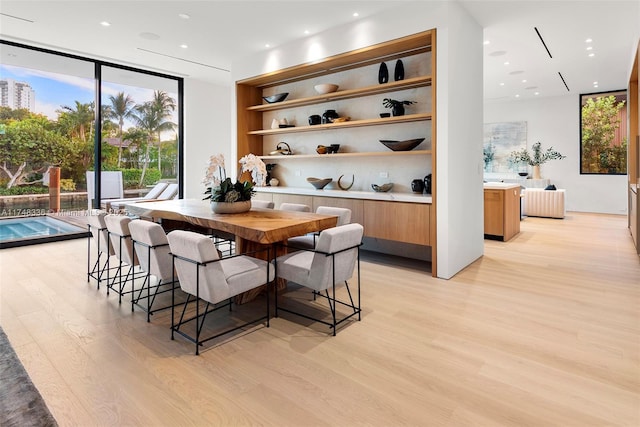 dining space with built in shelves, recessed lighting, floor to ceiling windows, and light wood-style flooring