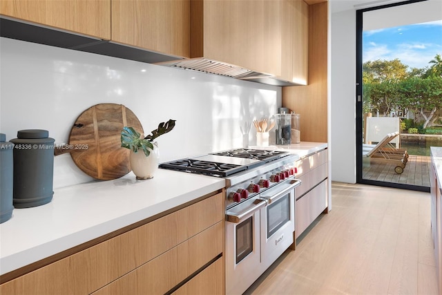 kitchen featuring double oven range, light brown cabinets, and light countertops