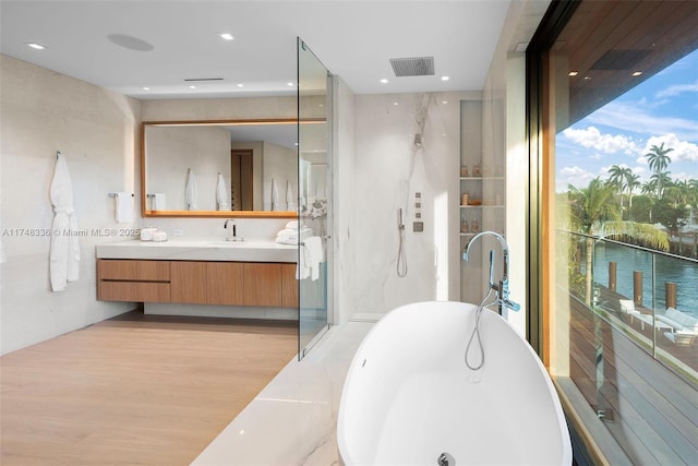 full bathroom with a marble finish shower, visible vents, wood finished floors, vanity, and a freestanding tub