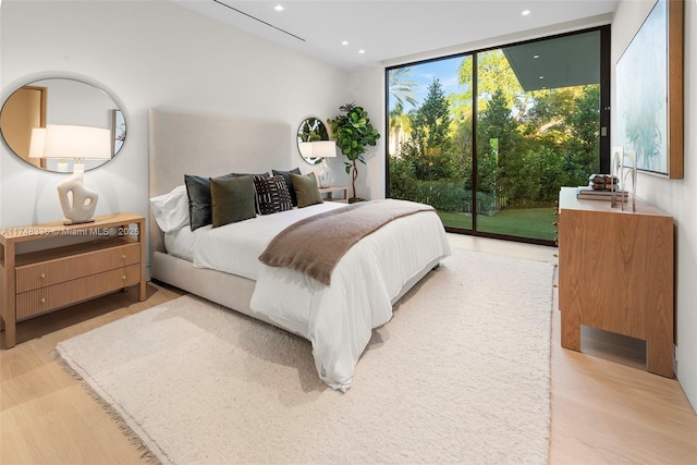 bedroom with expansive windows, access to outside, recessed lighting, and light wood-style floors