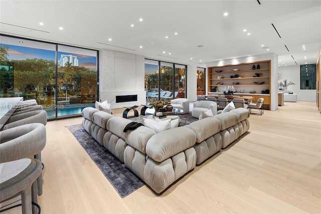 living room with light wood-style flooring, a wall of windows, and recessed lighting