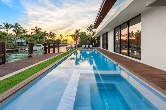 view of pool featuring a pool with connected hot tub, a water view, and a boat dock