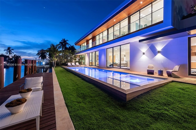 outdoor pool with a water view and a yard