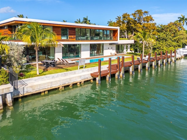 rear view of house with a patio, a water view, and an outdoor pool