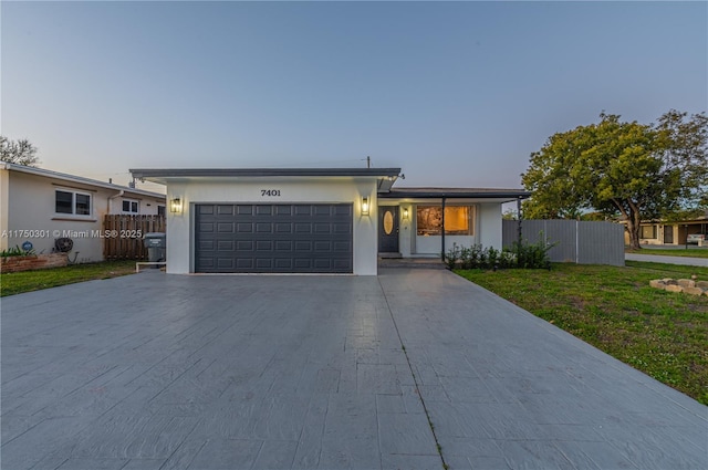 view of front facade with a garage, a yard, driveway, and fence