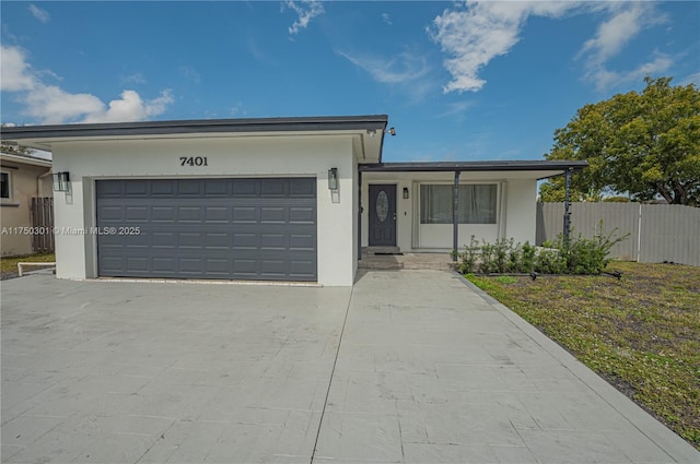 ranch-style house featuring an attached garage, fence, concrete driveway, stucco siding, and a front lawn