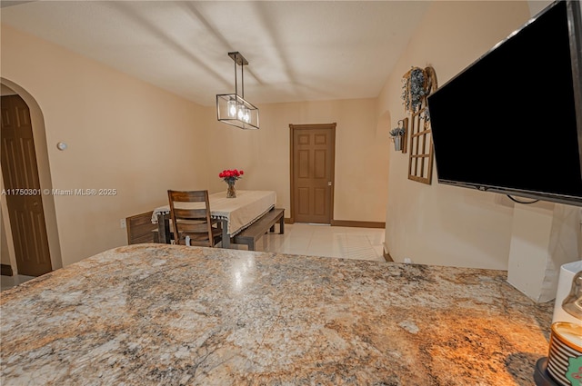 dining area with arched walkways, light tile patterned floors, and baseboards