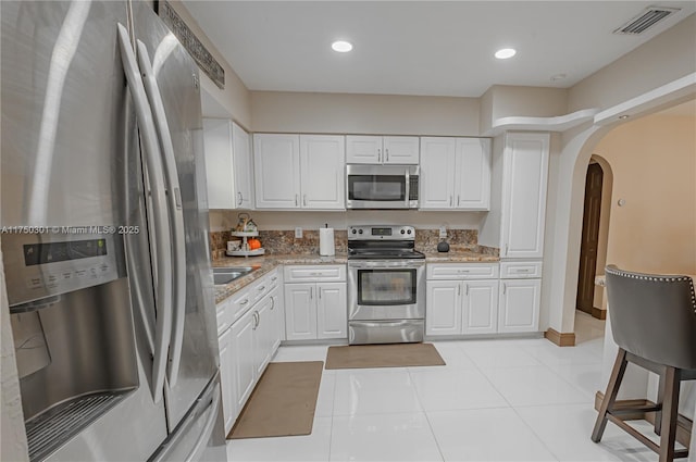 kitchen featuring light stone countertops, white cabinetry, visible vents, and appliances with stainless steel finishes