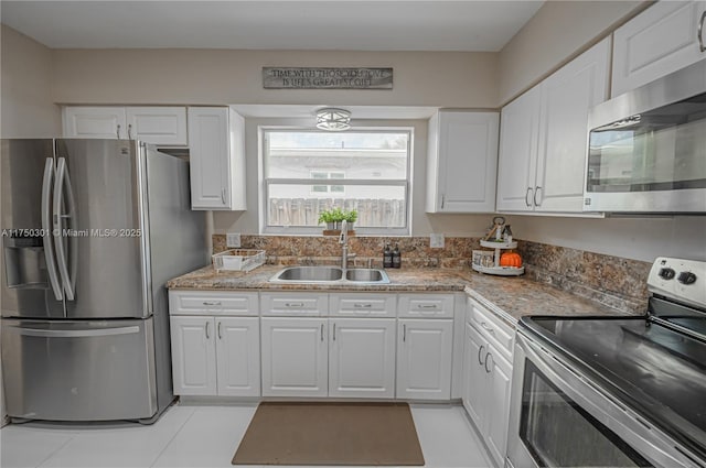 kitchen featuring stainless steel appliances, a sink, white cabinetry, and light stone countertops