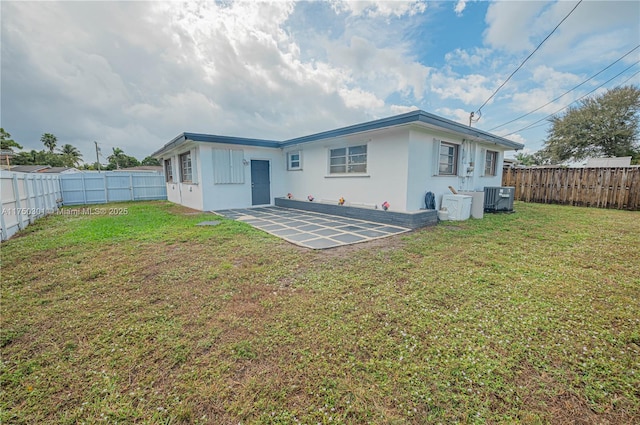 rear view of property featuring a fenced backyard, a lawn, central AC, and a patio