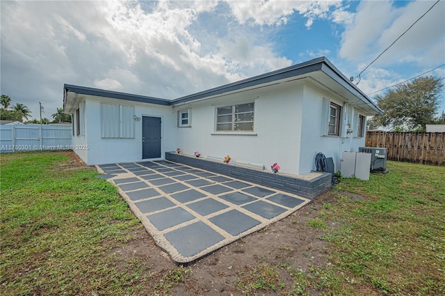 rear view of house featuring a fenced backyard, a lawn, and stucco siding